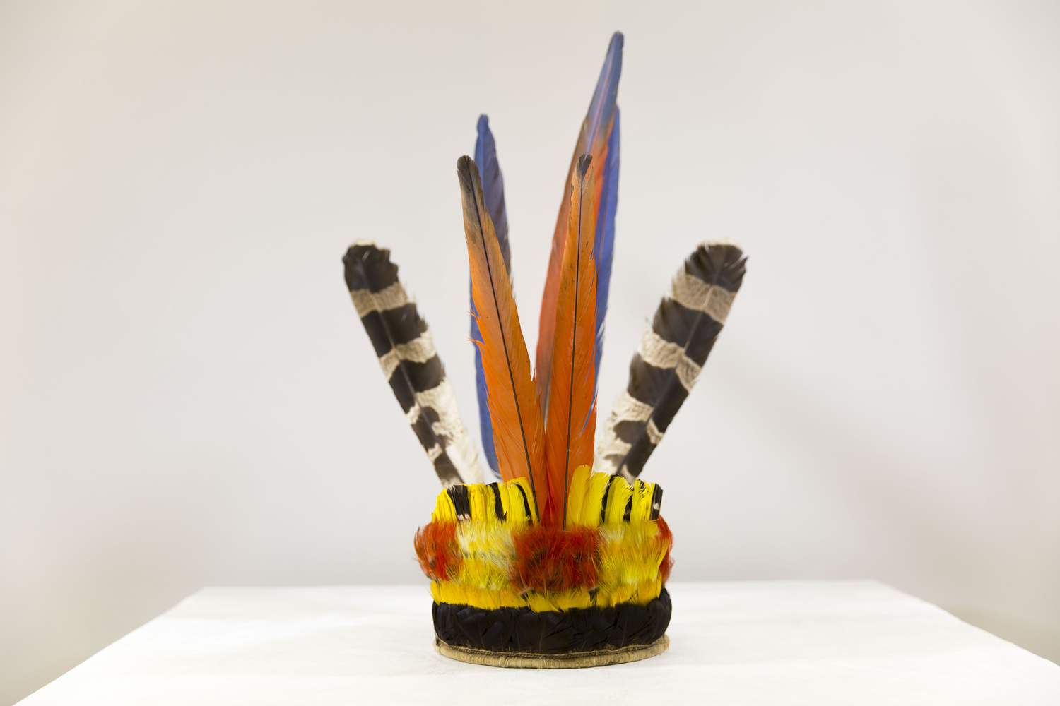 A crown woven with fiber and colorful feathers in red, orange and blue